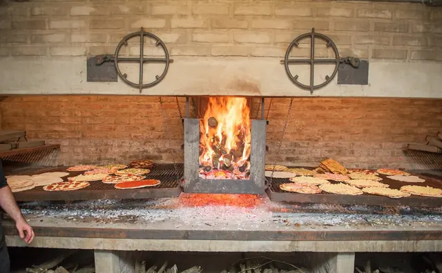 Horno a leña encendido con pizzas en la parrilla, en el Salón del Vino Fino de Salto
